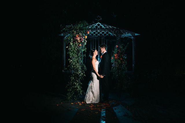 A wedding couple in a gazebo at night.