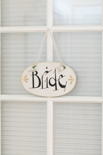 A sign that says "Bride" hanging from a window.